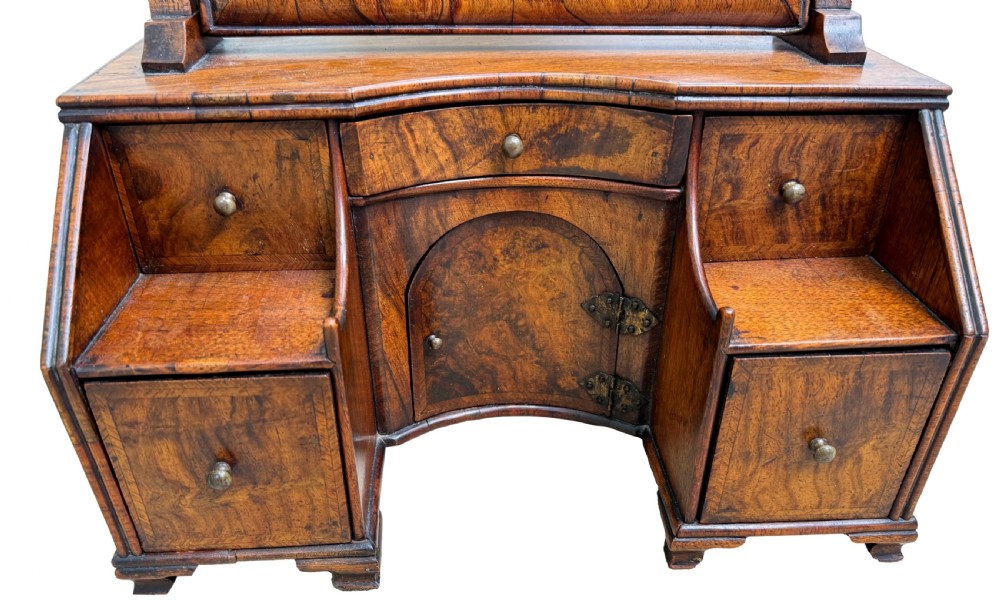 An early 18th-century Georgian walnut dressing table mirror featuring a shaped carved cresting, turned supports, and a base with miniature drawers and a central arch. View XII