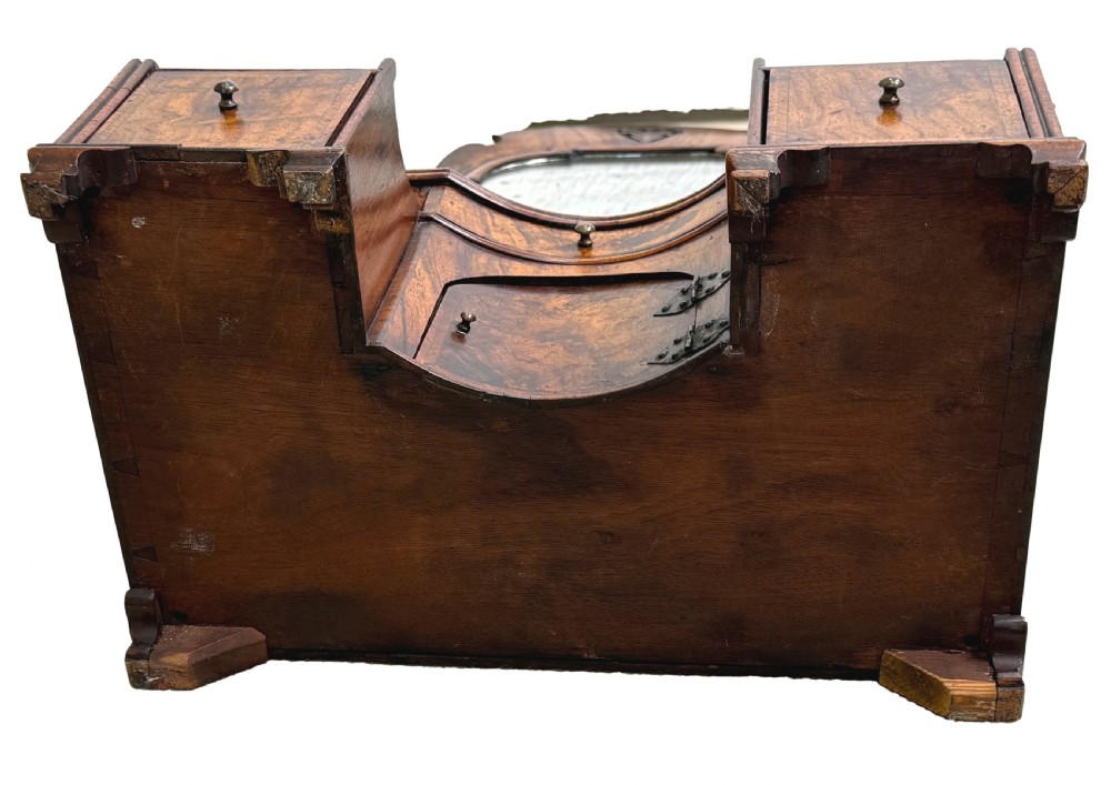 An early 18th-century Georgian walnut dressing table mirror featuring a shaped carved cresting, turned supports, and a base with miniature drawers and a central arch. View XV