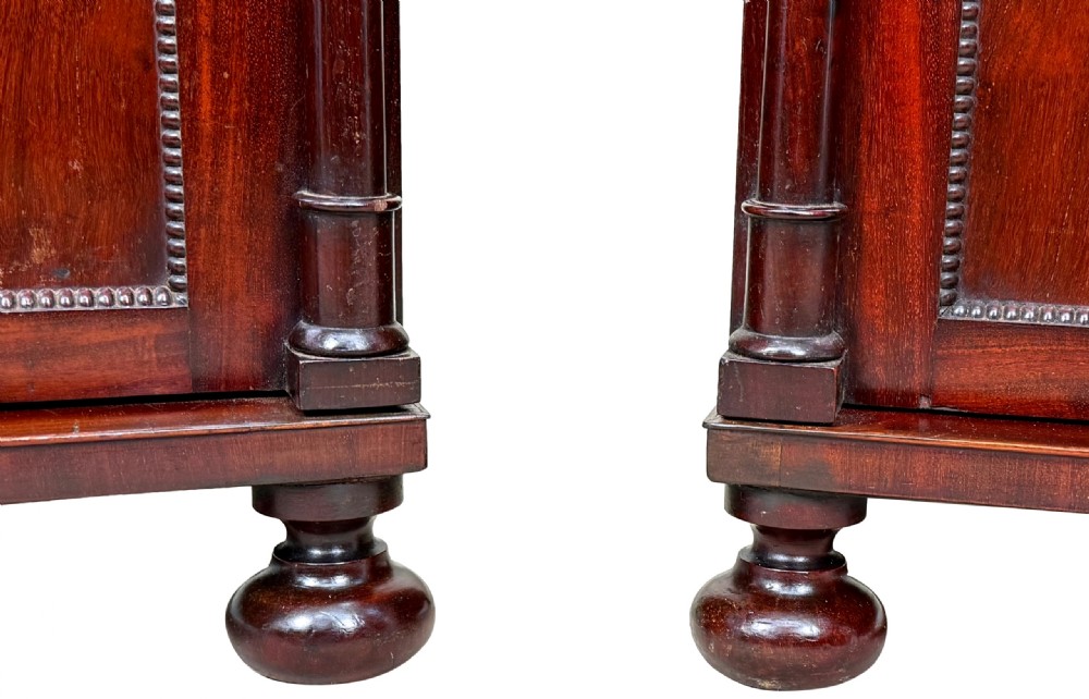 A pair of matching Regency mahogany side cupboards featuring flame veneer panel doors, flanking columns, and turned ball feet. View II
