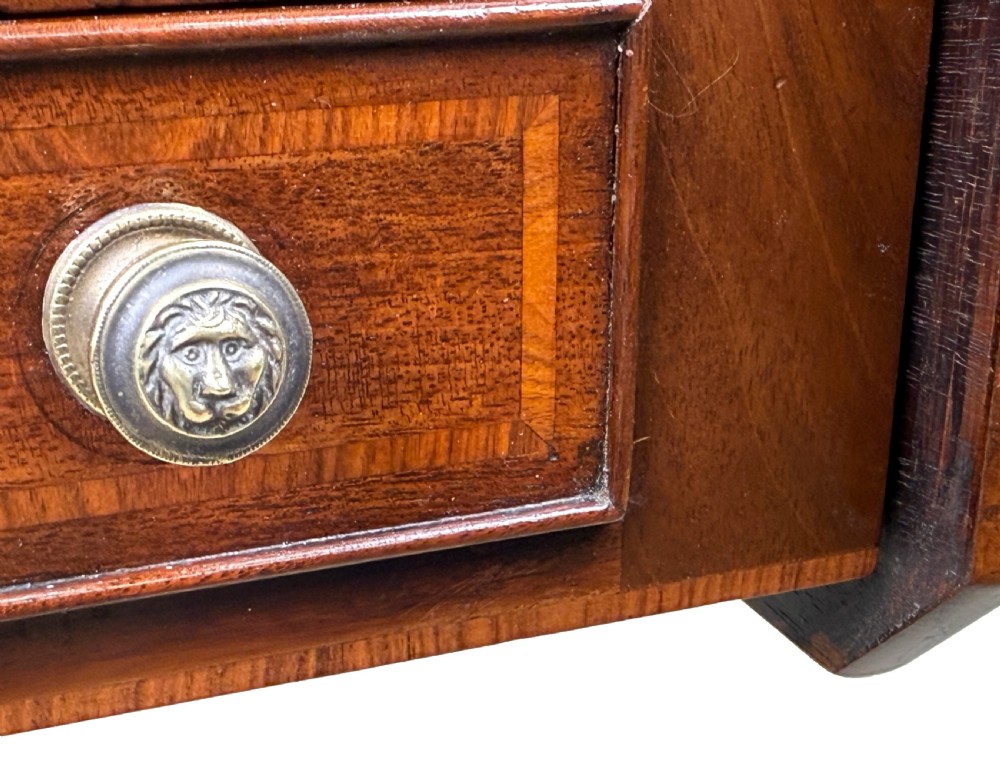 A Georgian mahogany baby Pembroke table with two drop leaves, double drawers with inlay, a turned central pedestal, and sabre tripod legs on brass castors. View V