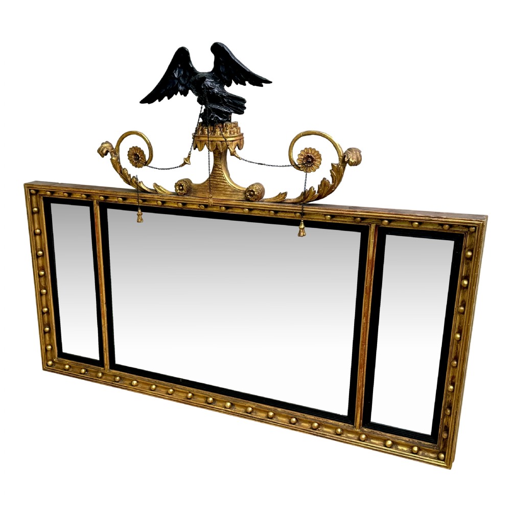 A Regency giltwood tripartite overmantel mirror featuring ball moulding details, ebonised inner slips, and an ebonised eagle crest surmount.
