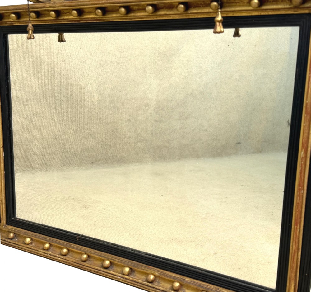A Regency giltwood tripartite overmantel mirror featuring ball moulding details, ebonised inner slips, and an ebonised eagle crest surmount. View V