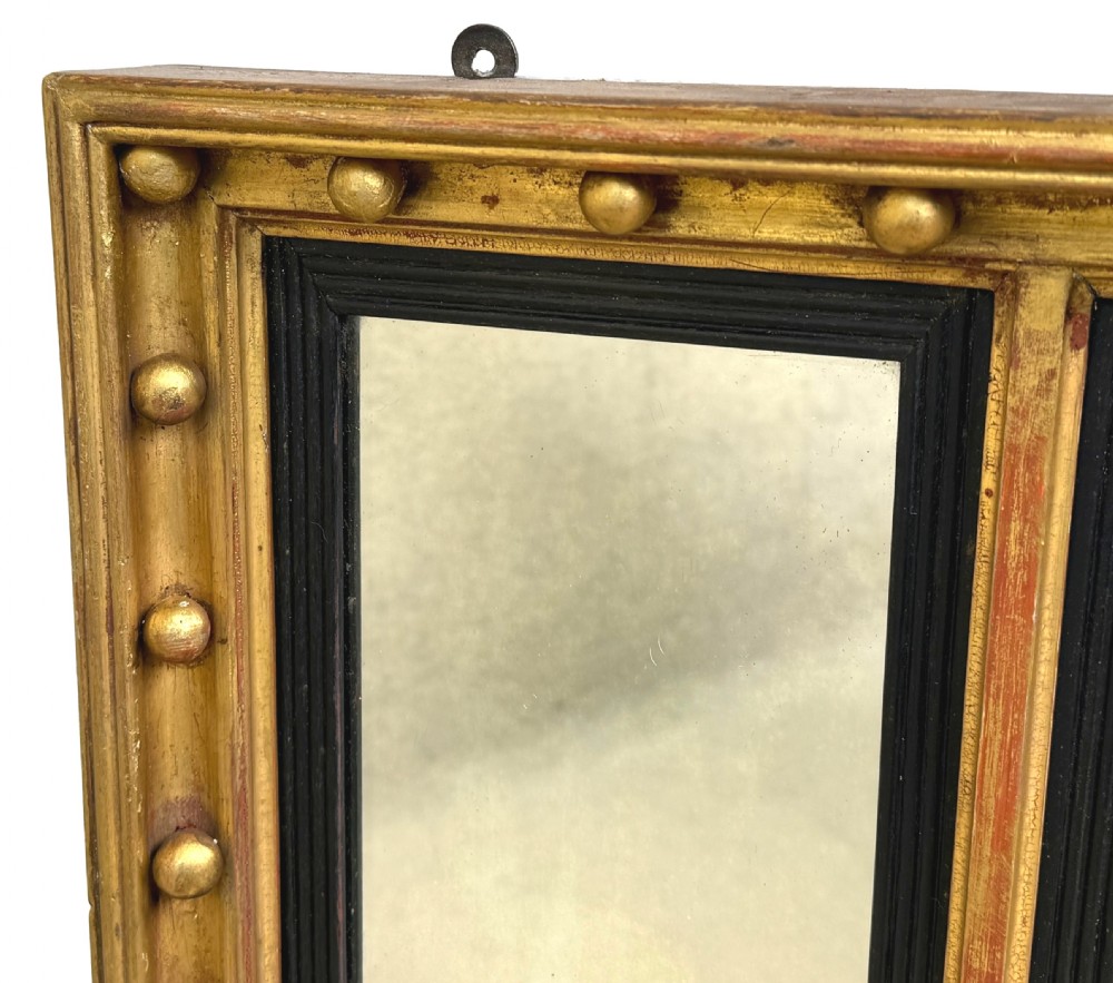 A Regency giltwood tripartite overmantel mirror featuring ball moulding details, ebonised inner slips, and an ebonised eagle crest surmount. View VII