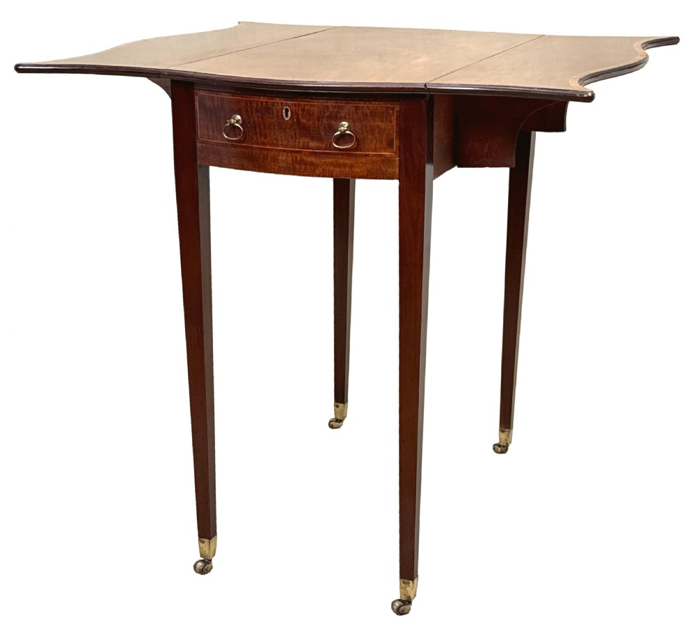 An 18th-century Hepplewhite mahogany Pembroke table with extended shaped drop leaves, a single drawer, and tapered legs on brass castors.