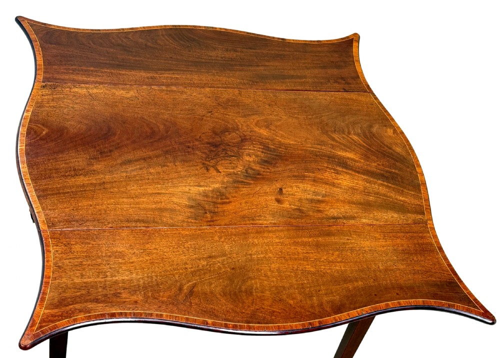 An 18th-century Hepplewhite mahogany Pembroke table with extended shaped drop leaves, a single drawer, and tapered legs on brass castors. View V