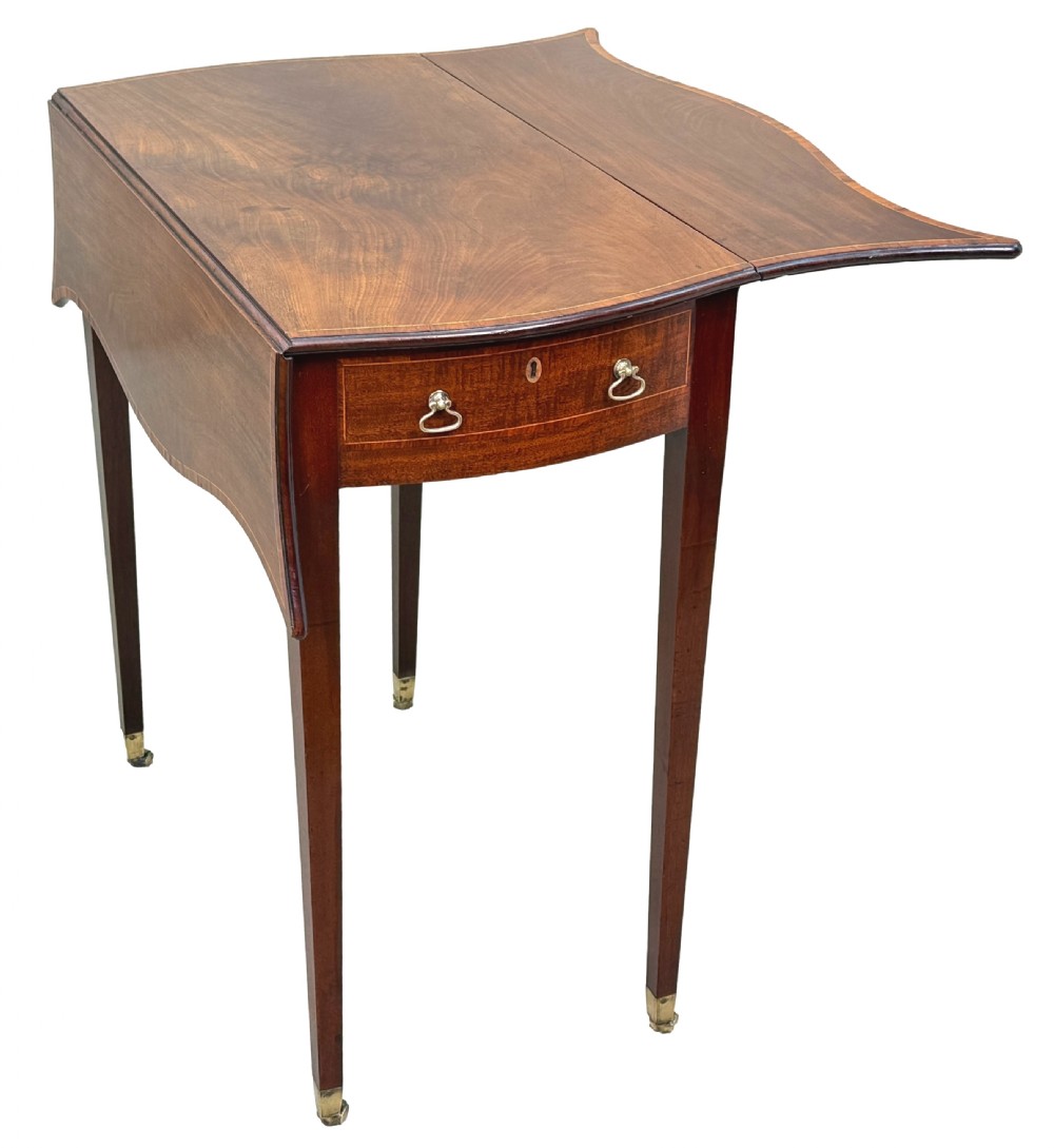 An 18th-century Hepplewhite mahogany Pembroke table with extended shaped drop leaves, a single drawer, and tapered legs on brass castors. View VI