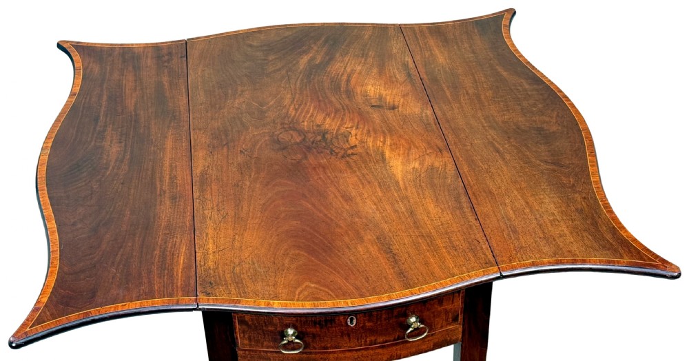 An 18th-century Hepplewhite mahogany Pembroke table with extended shaped drop leaves, a single drawer, and tapered legs on brass castors. View XII
