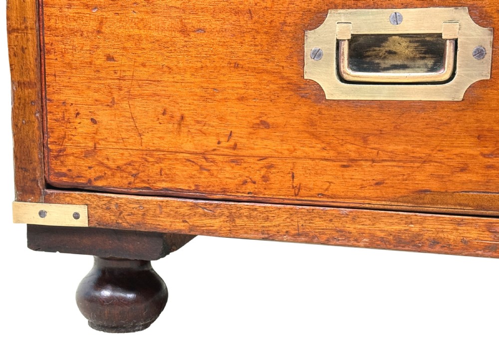 A nineteenth-century camphor wood military campaign chest of drawers featuring flush brass handles, corner brackets, and turned bun feet. View IX