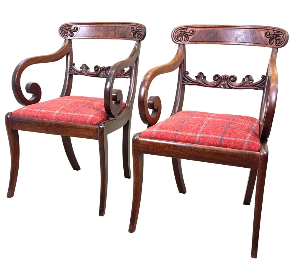 A pair of Regency mahogany carver armchairs featuring scrolled arms, carved back rails, and red plaid upholstered drop-in seats.