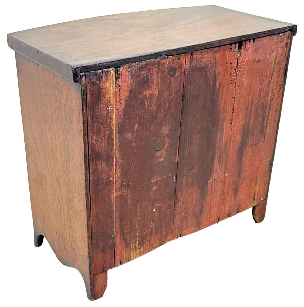 A 19th-century Victorian miniature mahogany bowfront chest featuring two short over three long graduated drawers with brass knobs and keyholes. View VIII