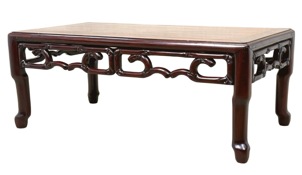 A 19th-century Chinese hardwood coffee table with a rectangular inset top, openwork carved bamboo apron, and low legs.
