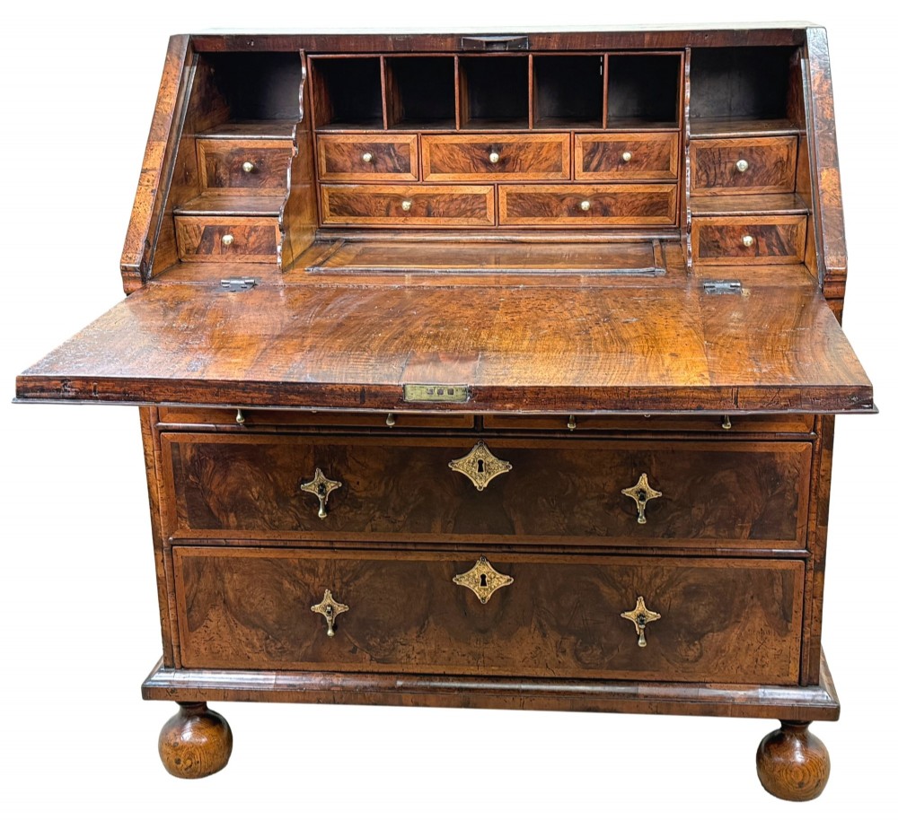 An early 18th-century Queen Anne walnut bureau featuring a slanted fall-front writing flap, brass escutcheons with drop handles, and turned bun feet. View IV
