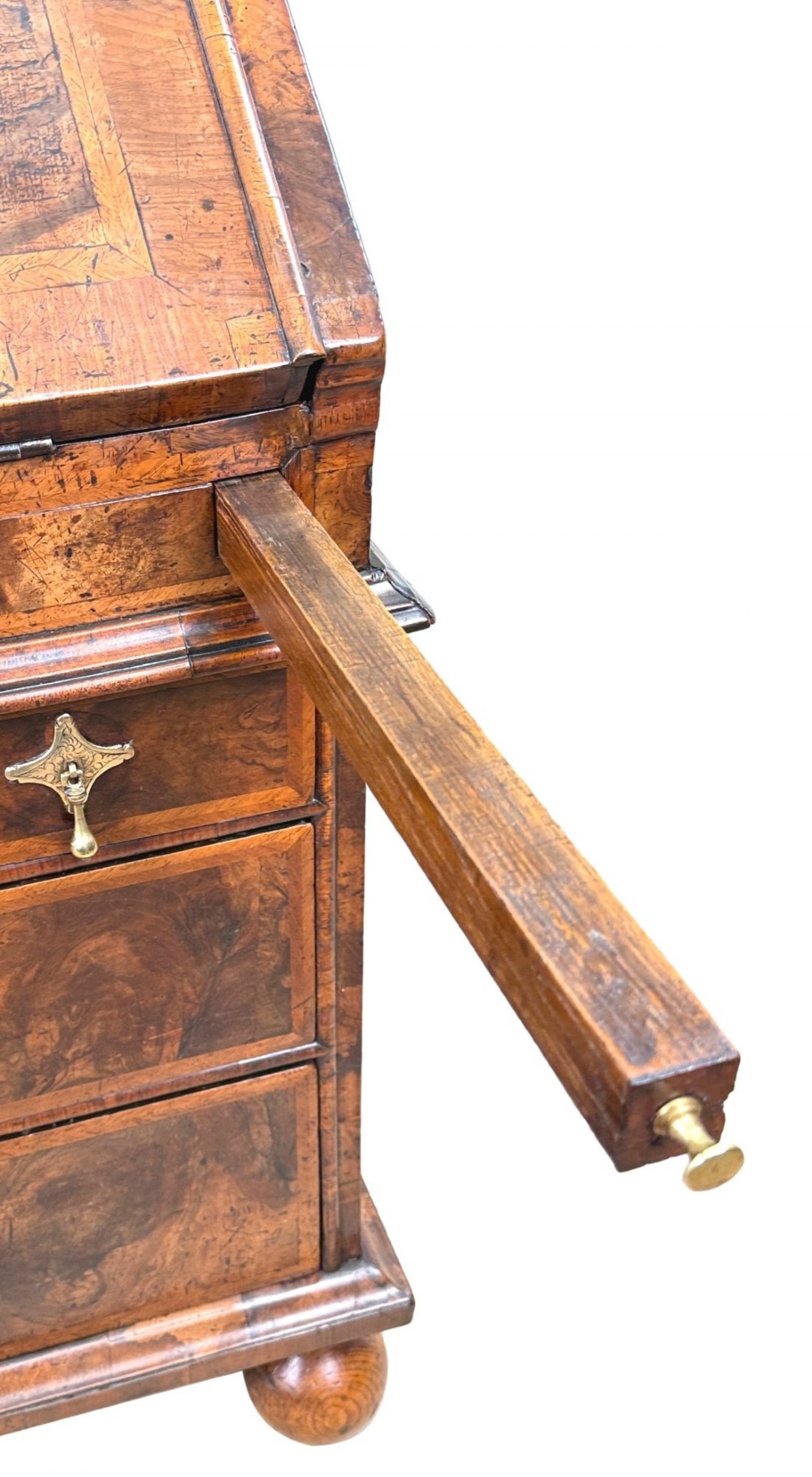 An early 18th-century Queen Anne walnut bureau featuring a slanted fall-front writing flap, brass escutcheons with drop handles, and turned bun feet. View V