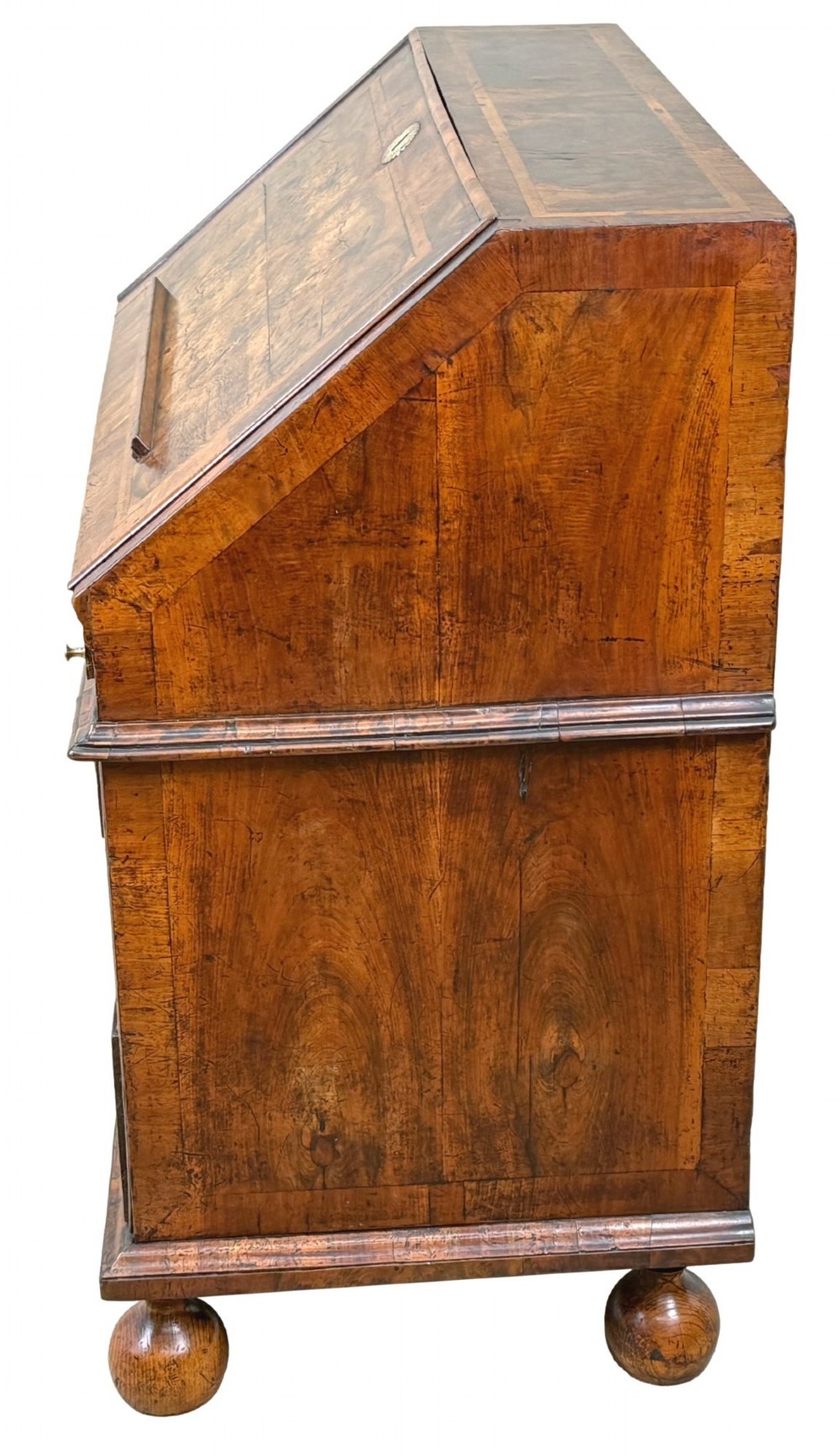 An early 18th-century Queen Anne walnut bureau featuring a slanted fall-front writing flap, brass escutcheons with drop handles, and turned bun feet. View VI