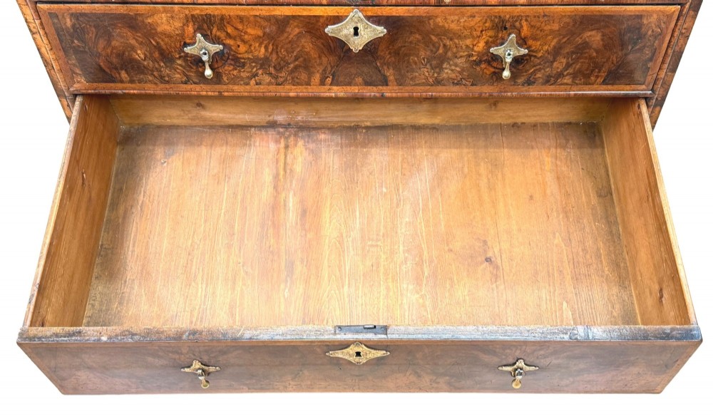 An early 18th-century Queen Anne walnut bureau featuring a slanted fall-front writing flap, brass escutcheons with drop handles, and turned bun feet. View VIII