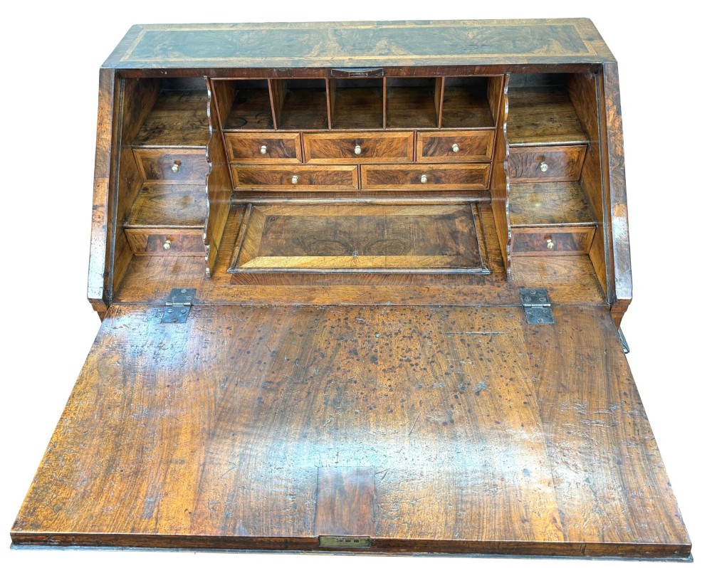 An early 18th-century Queen Anne walnut bureau featuring a slanted fall-front writing flap, brass escutcheons with drop handles, and turned bun feet. View XI
