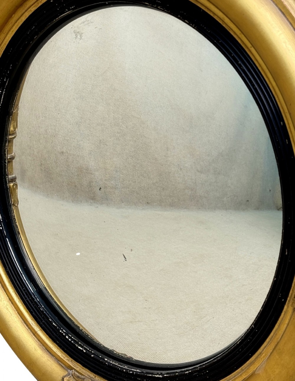 A mid-19th century circular convex mirror featuring a moulded giltwood frame with carved leaf clasps and an inner ebonised reeded slip. View VIII