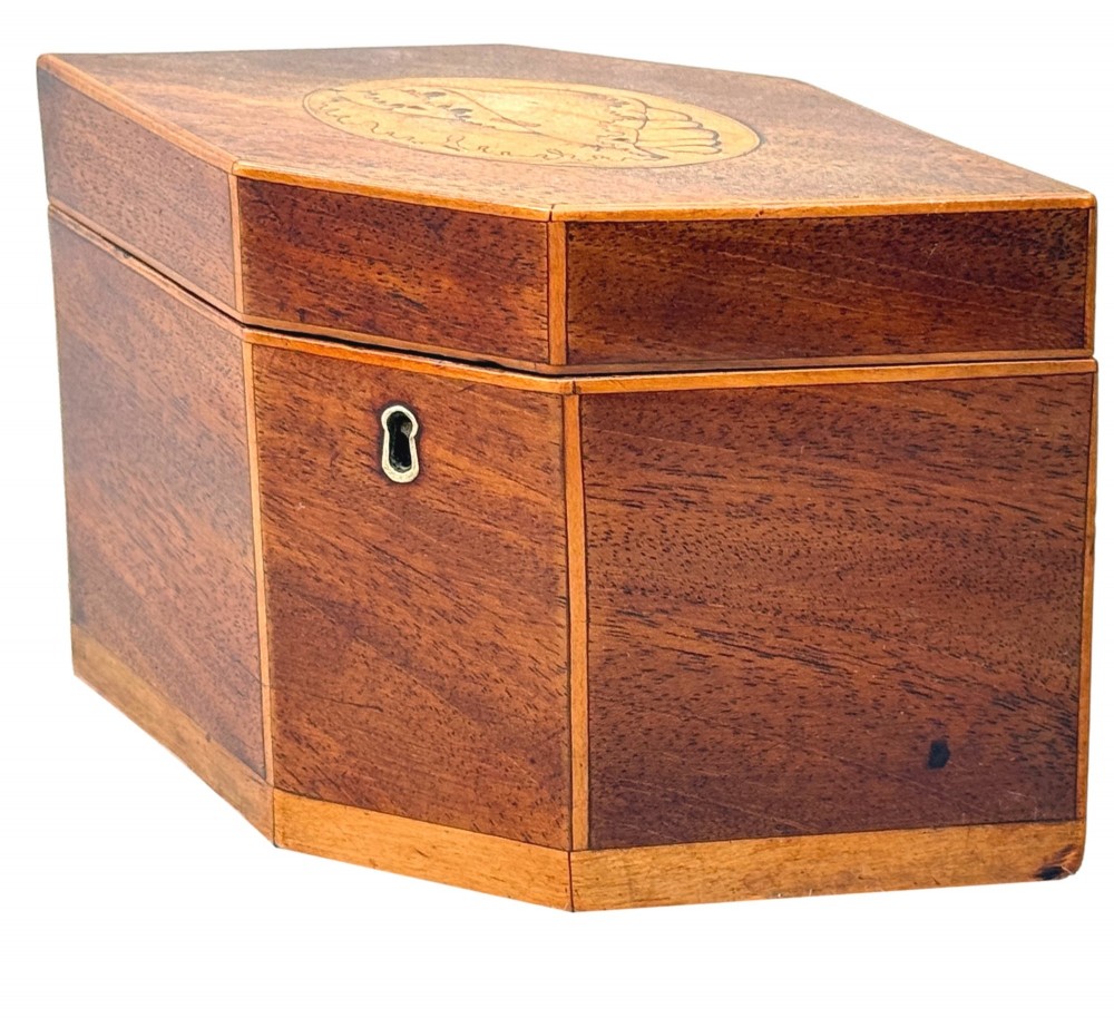 An 18th-century Georgian hexagonal mahogany tea caddy with line inlay and a shell medallion on the lid.