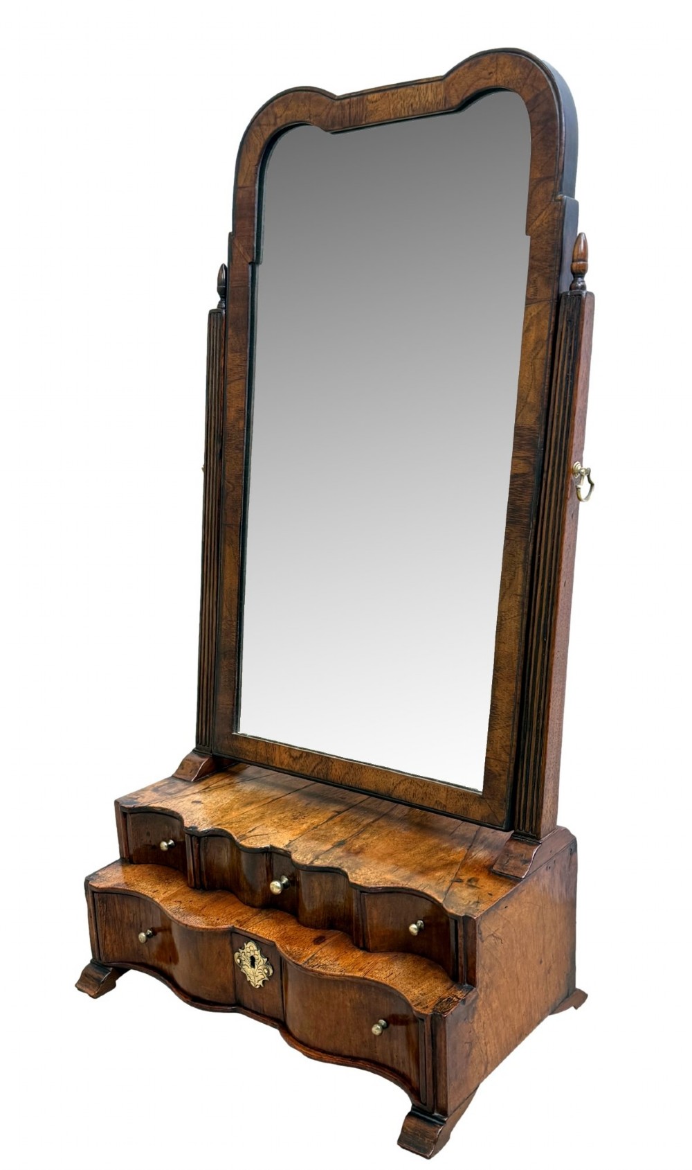 A Queen Anne early 18th-century walnut dressing table mirror featuring an arched swing frame resting above a stepped serpentine base with small drawers and brass hardware.