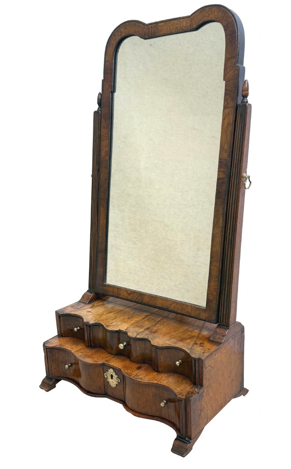 A Queen Anne early 18th-century walnut dressing table mirror featuring an arched swing frame resting above a stepped serpentine base with small drawers and brass hardware. View II