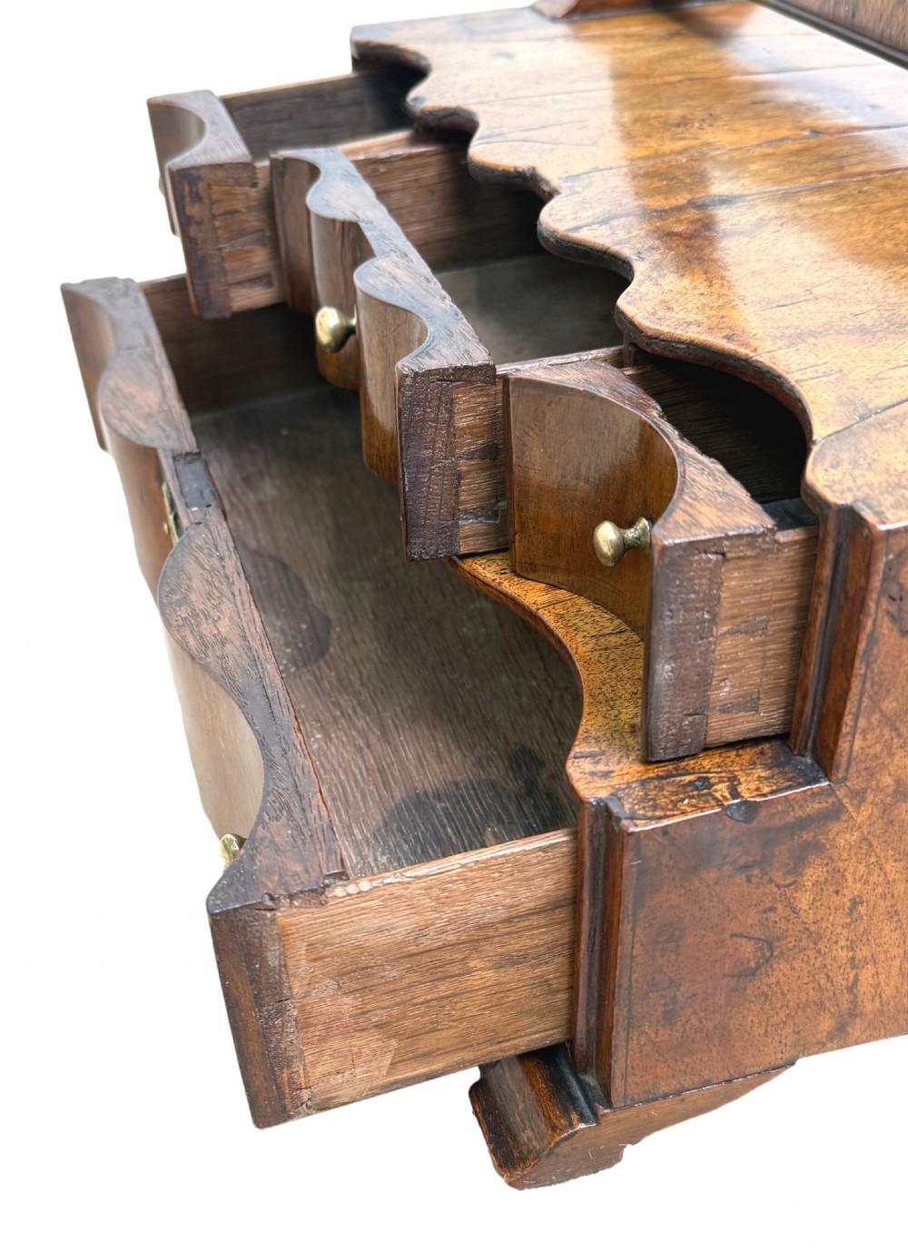 A Queen Anne early 18th-century walnut dressing table mirror featuring an arched swing frame resting above a stepped serpentine base with small drawers and brass hardware. View VII