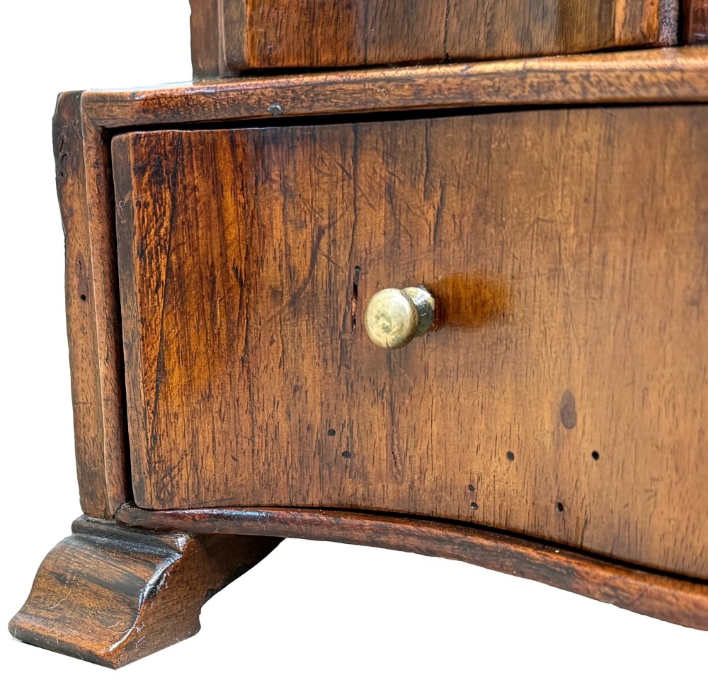 A Queen Anne early 18th-century walnut dressing table mirror featuring an arched swing frame resting above a stepped serpentine base with small drawers and brass hardware. View X