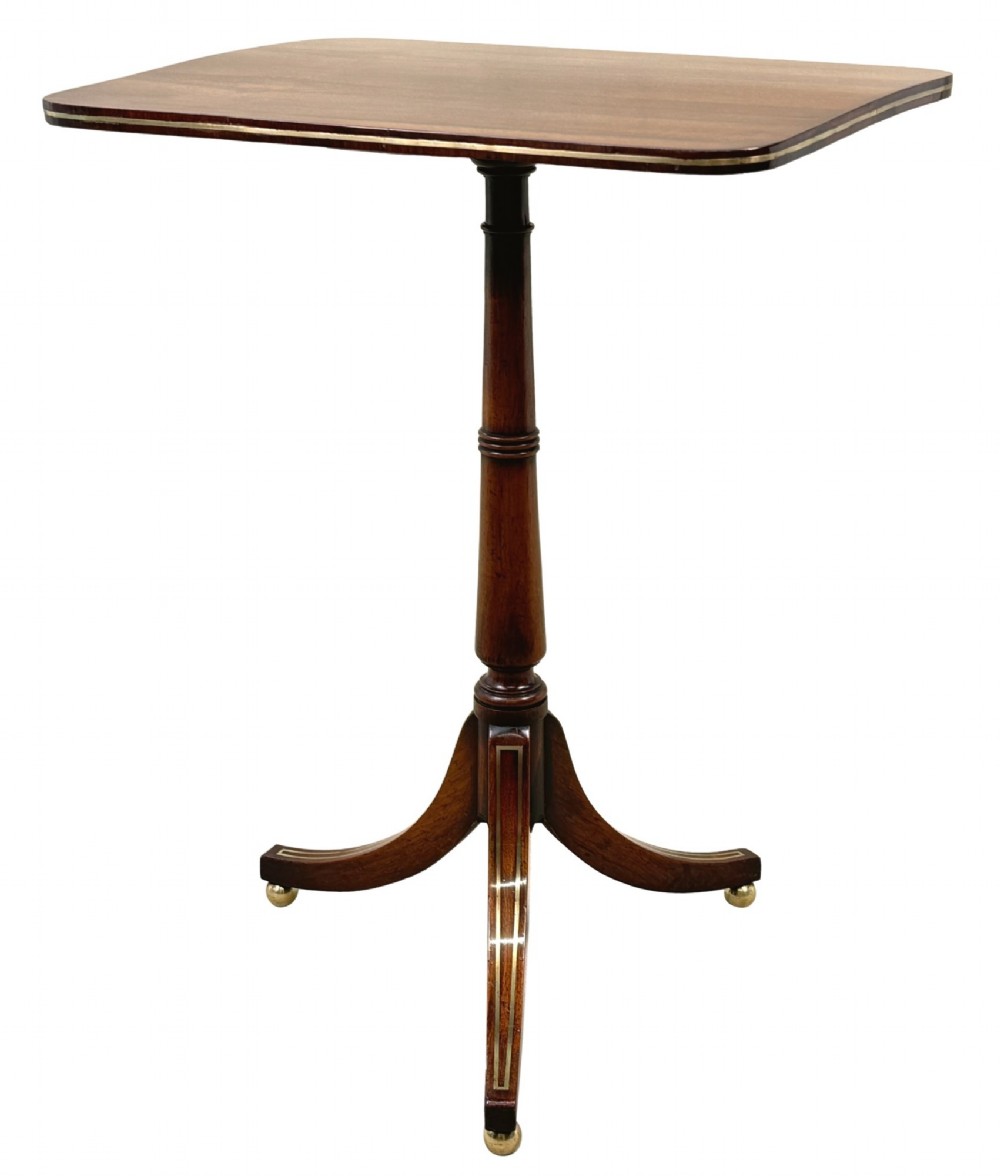 A nineteenth-century Regency rosewood occasional table featuring a rectangular top with rounded corners, fine brass inlay stringing, a turned central column, and a tripod base resting on brass feet.