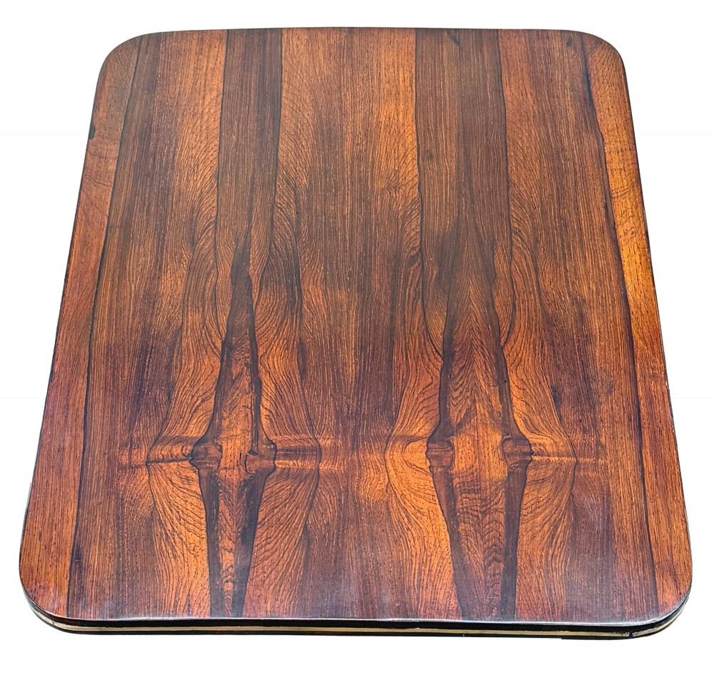 A nineteenth-century Regency rosewood occasional table featuring a rectangular top with rounded corners, fine brass inlay stringing, a turned central column, and a tripod base resting on brass feet. View VII