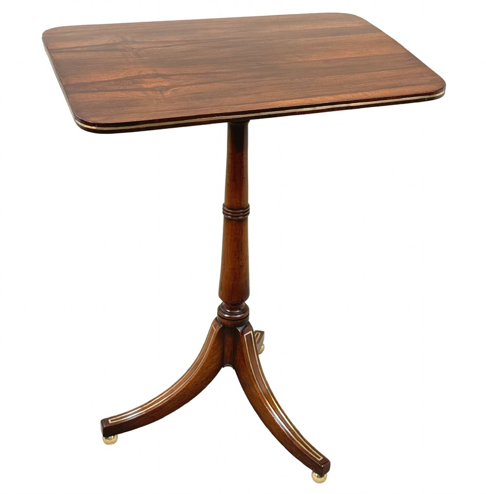 A nineteenth-century Regency rosewood occasional table featuring a rectangular top with rounded corners, fine brass inlay stringing, a turned central column, and a tripod base resting on brass feet. View VIII