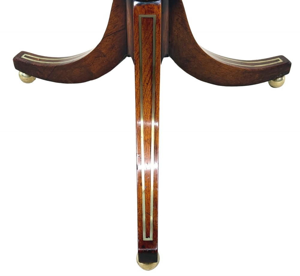 A nineteenth-century Regency rosewood occasional table featuring a rectangular top with rounded corners, fine brass inlay stringing, a turned central column, and a tripod base resting on brass feet. View IX