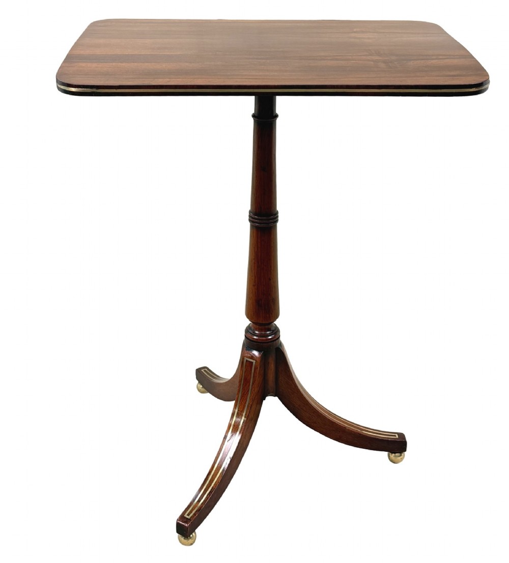 A nineteenth-century Regency rosewood occasional table featuring a rectangular top with rounded corners, fine brass inlay stringing, a turned central column, and a tripod base resting on brass feet. View X