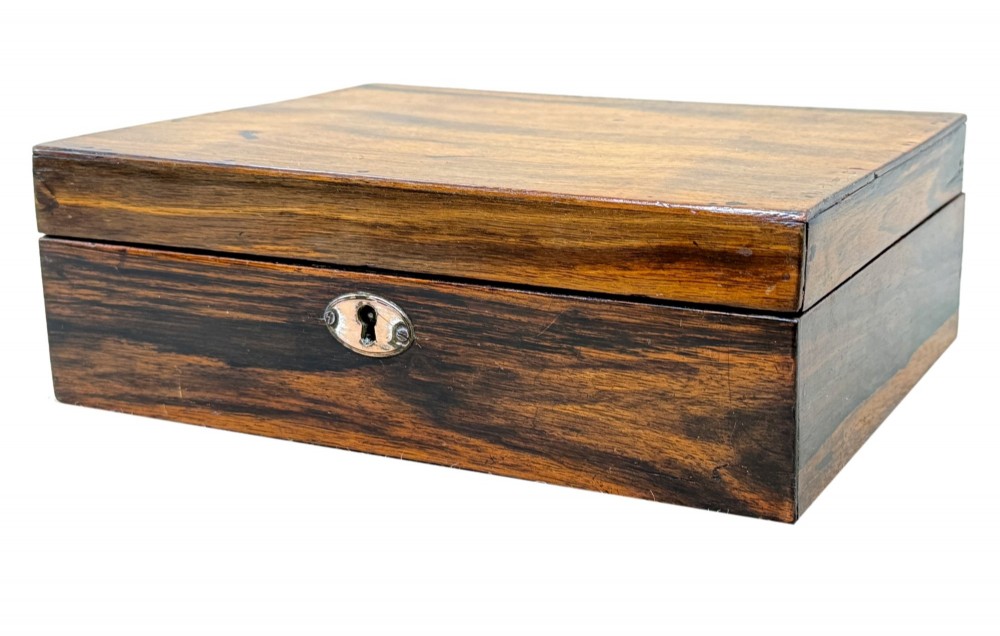 A 19th-century rectangular coromandel wood work box featuring a hinged lid, rich striped graining, and a central escutcheon.