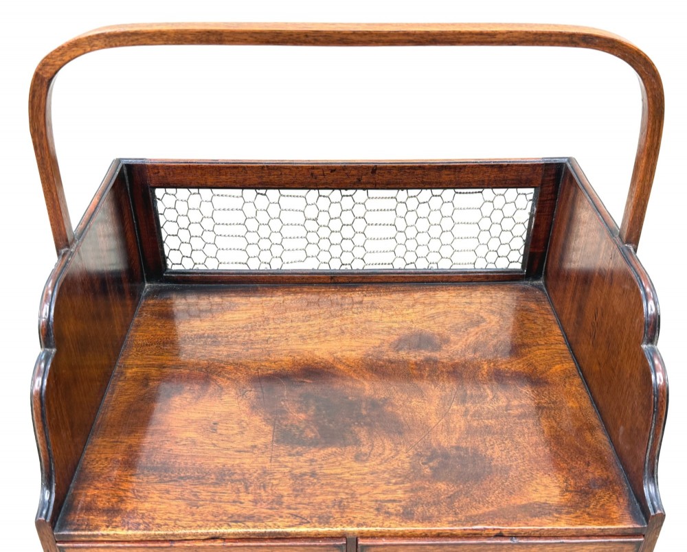 An 18th-century Georgian mahogany book carrier featuring a curved wooden top handle, a rear wire mesh panel, shaped side galleries, and three small drawers fitted with brass drop ring handles. View VII
