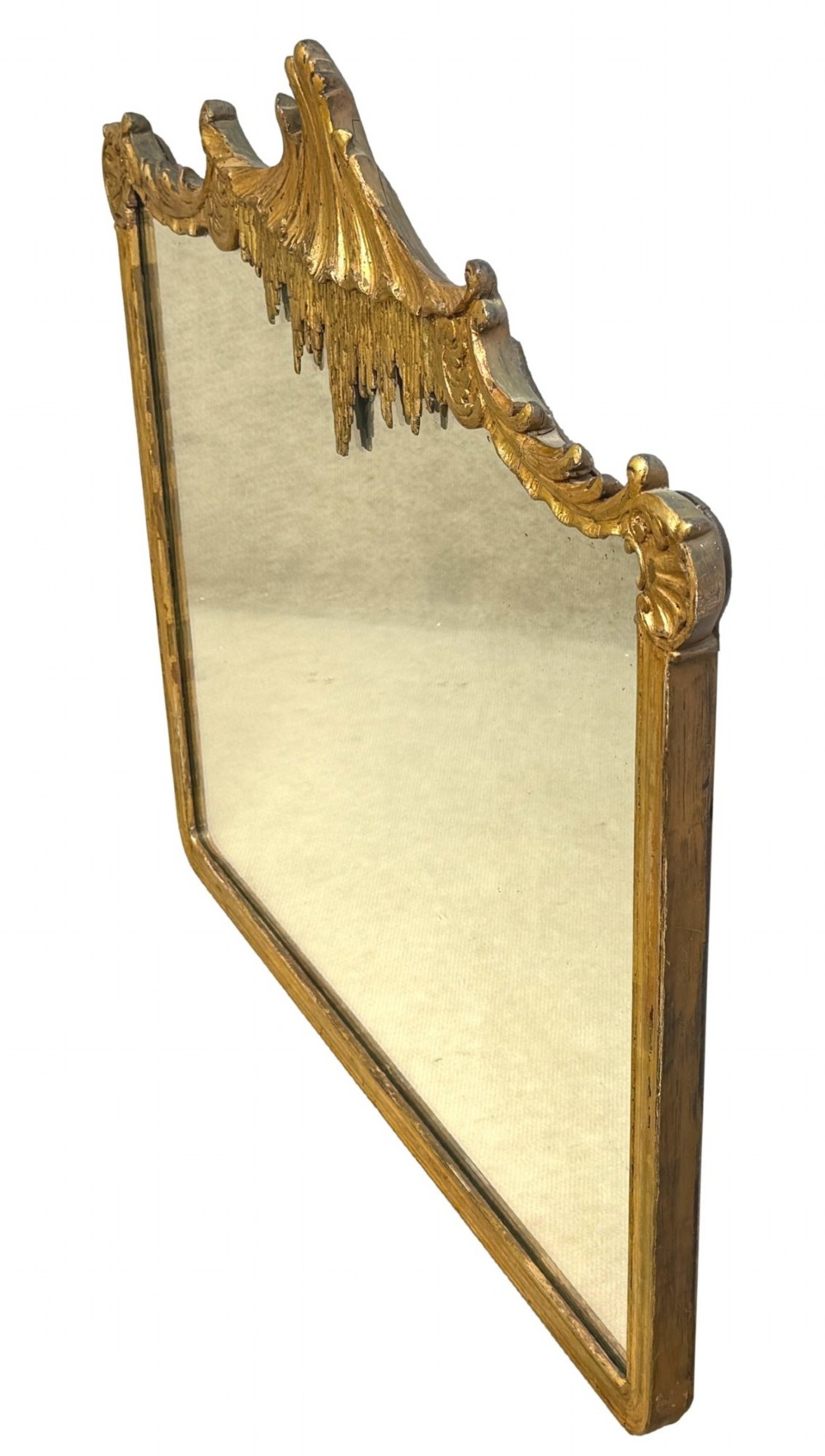 A late 19th-century giltwood wall mirror featuring a carved gesso cresting with scrollwork and dripping fringe details above a rectangular glass panel. View IV