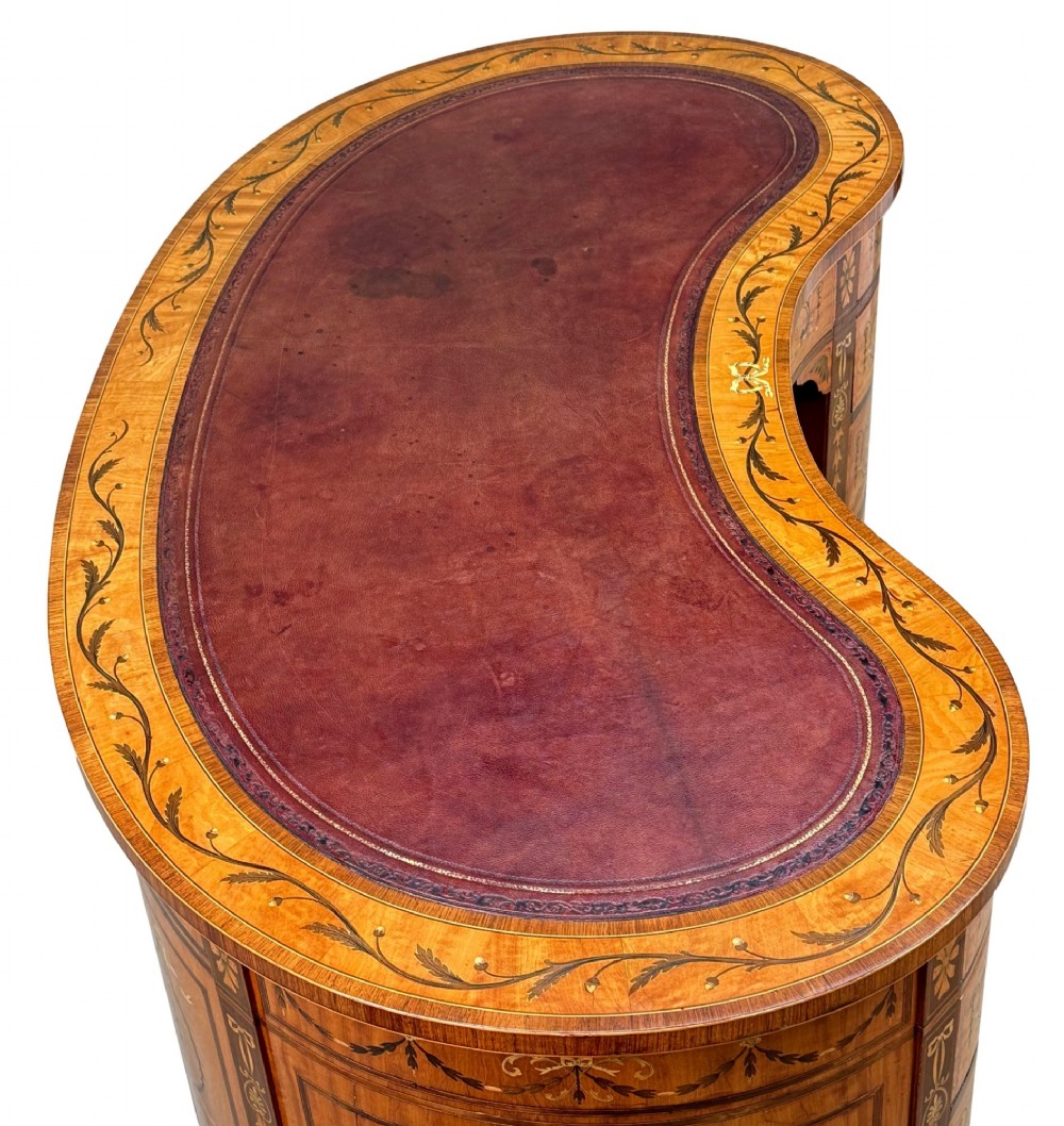 A late nineteenth-century kidney-shaped satinwood writing desk with detailed floral marquetry inlays, twin pedestals, and a leather insert top. View IV