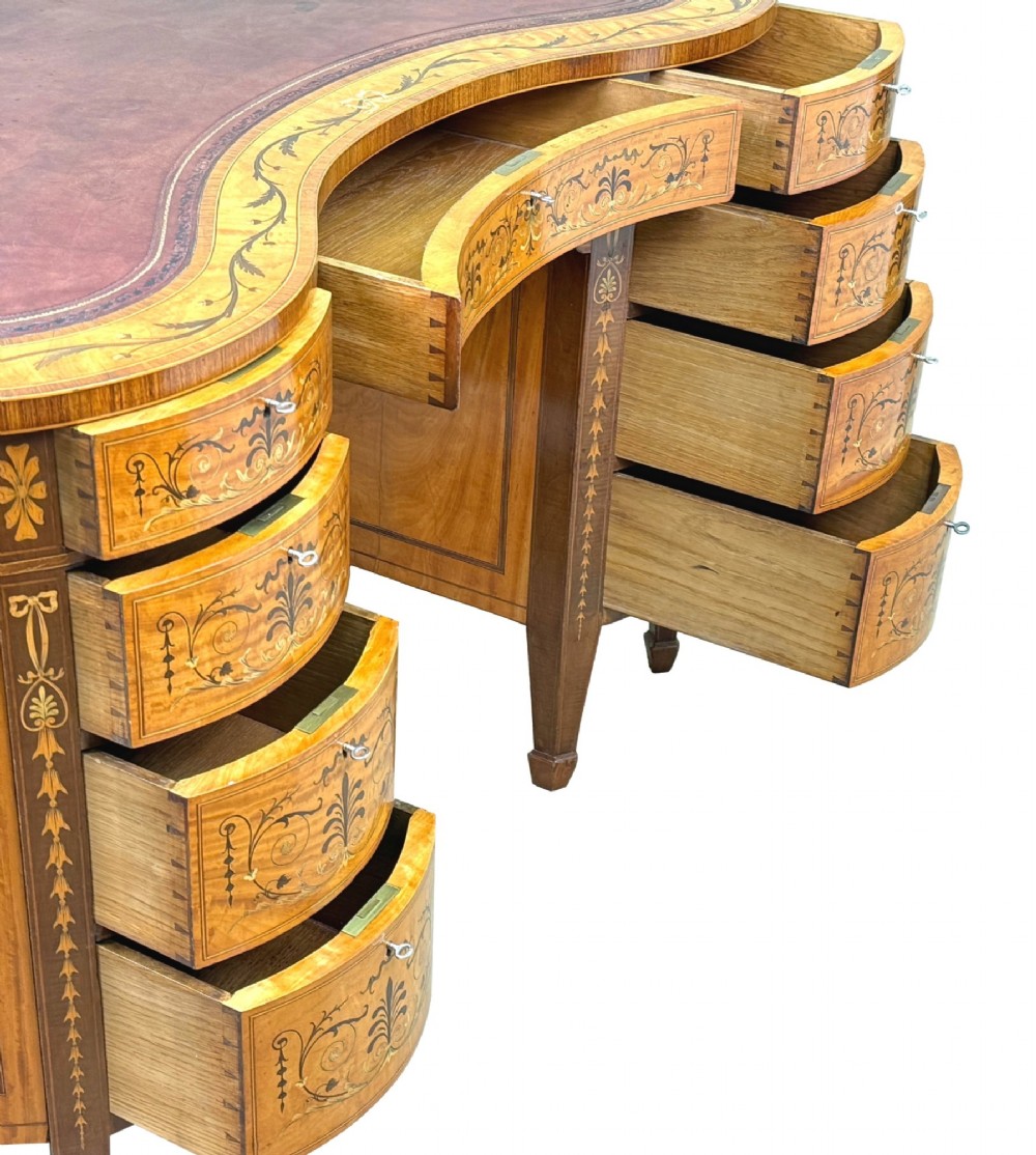 A late nineteenth-century kidney-shaped satinwood writing desk with detailed floral marquetry inlays, twin pedestals, and a leather insert top. View V