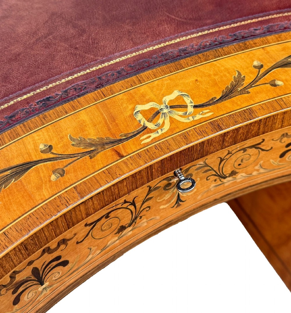 A late nineteenth-century kidney-shaped satinwood writing desk with detailed floral marquetry inlays, twin pedestals, and a leather insert top. View IX