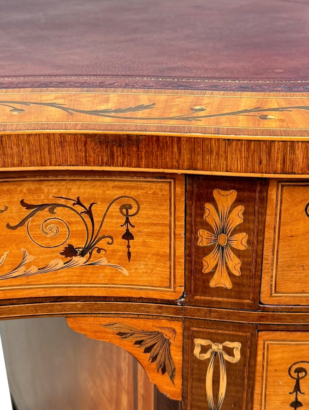A late nineteenth-century kidney-shaped satinwood writing desk with detailed floral marquetry inlays, twin pedestals, and a leather insert top. View X