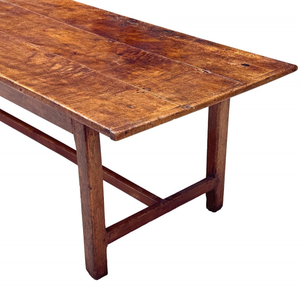 An 18th-century English farmhouse dining table crafted from warm brown oak with a wide three-plank top, plain apron, and an H-stretcher base. View II