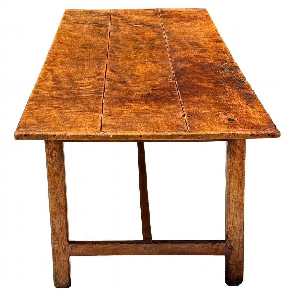 An 18th-century English farmhouse dining table crafted from warm brown oak with a wide three-plank top, plain apron, and an H-stretcher base. View V