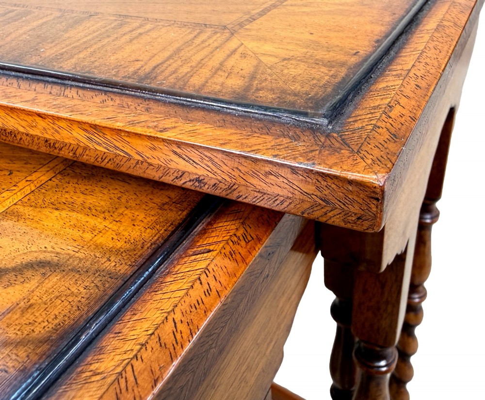 A set of four early twentieth-century brown walnut nesting tables featuring barley twist legs, arched stretchers, and banded inlaid tops stacked in graduated size. View II