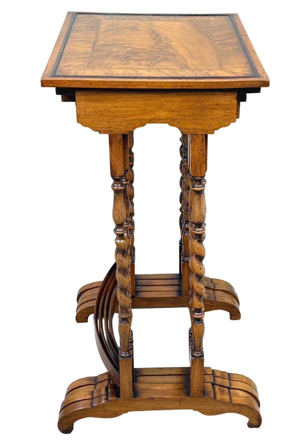 A set of four early twentieth-century brown walnut nesting tables featuring barley twist legs, arched stretchers, and banded inlaid tops stacked in graduated size. View V