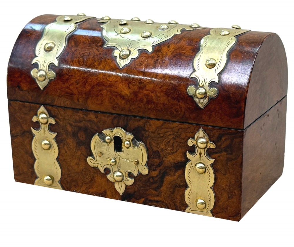 A nineteenth-century domed stationery box crafted from highly figured burr walnut with ornamental brass strapwork and studs.