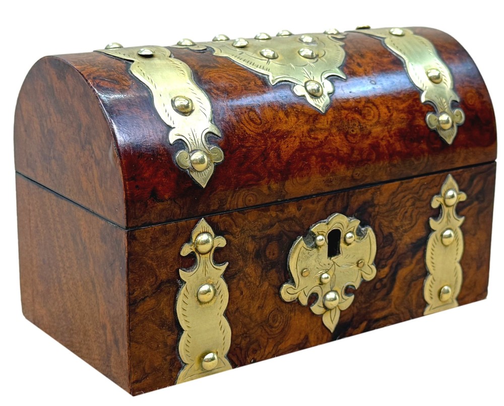 A nineteenth-century domed stationery box crafted from highly figured burr walnut with ornamental brass strapwork and studs. View X