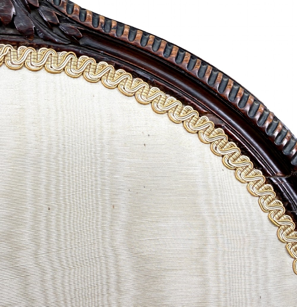 An 18th-century Georgian mahogany salon chair featuring an oval back rest, carved wooden frame, and cream silk upholstery. View X