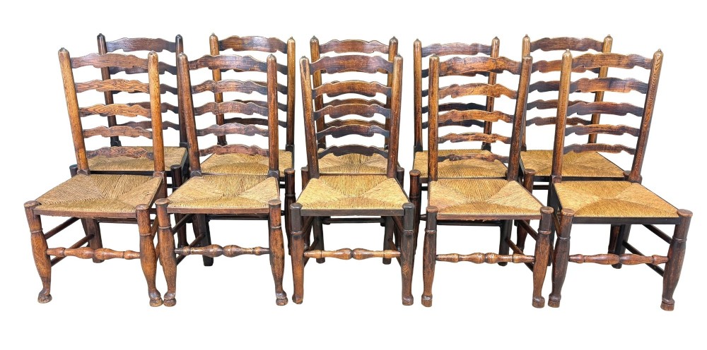 A set of ten early 19th-century Georgian country dining chairs featuring waved ladderback slats, woven rush seats, and turned wooden legs.