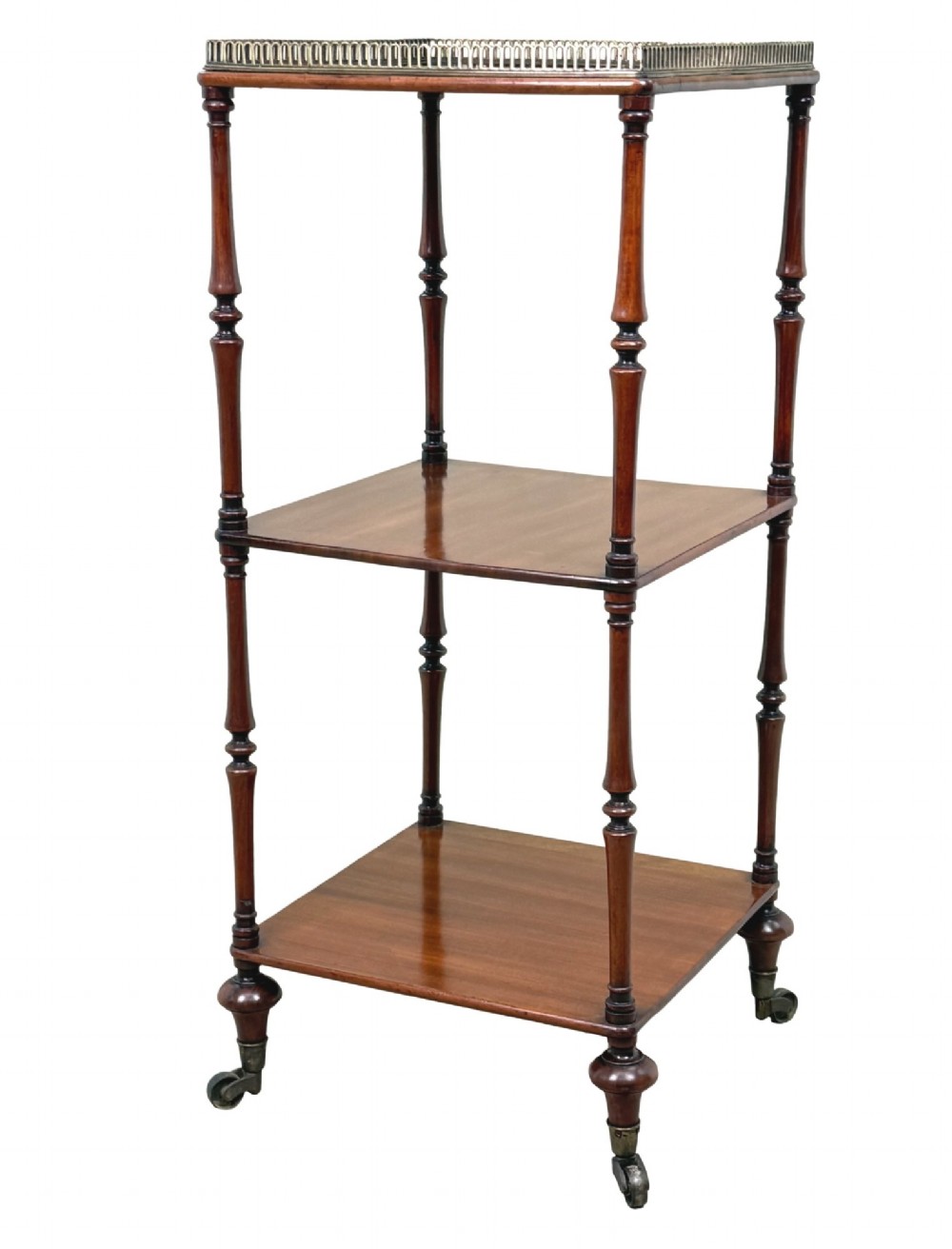 A three-tier Regency mahogany whatnot featuring a pierced brass gallery top rail, turned support columns, and brass castors.