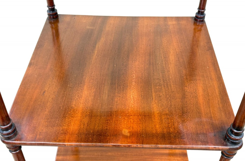 A three-tier Regency mahogany whatnot featuring a pierced brass gallery top rail, turned support columns, and brass castors. View IV
