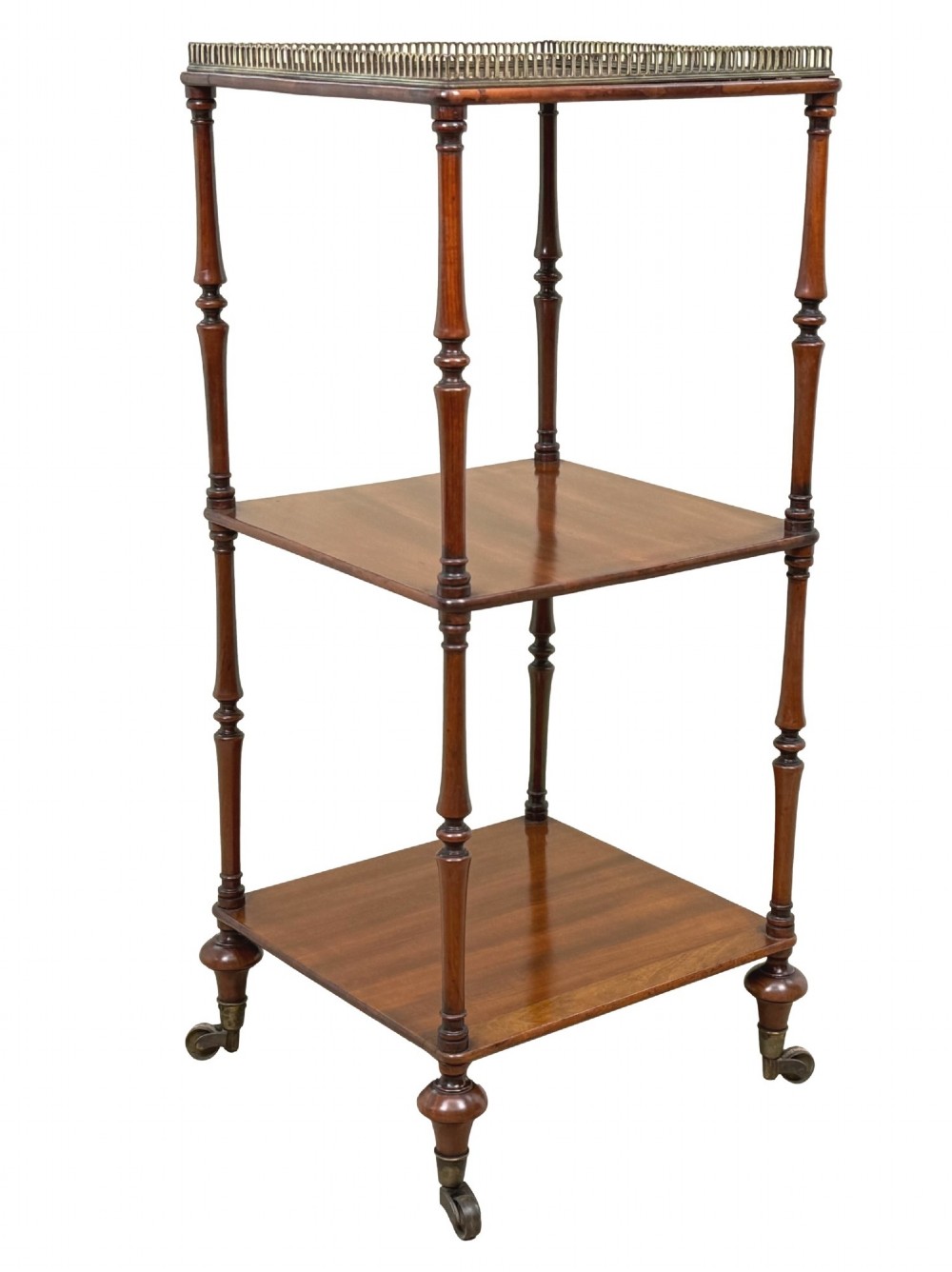 A three-tier Regency mahogany whatnot featuring a pierced brass gallery top rail, turned support columns, and brass castors. View V