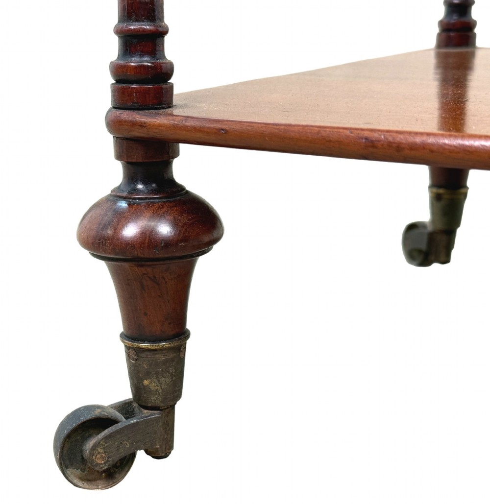 A three-tier Regency mahogany whatnot featuring a pierced brass gallery top rail, turned support columns, and brass castors. View X